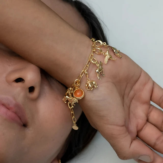 Lily Charmed gold oval link charm bracelet in 18ct gold-plated recycled sterling silver with charms on a wrist 