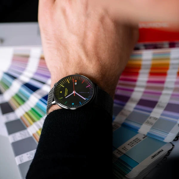 Mondaine Doppio 41mm black Swiss watch with colourful Bauhaus dial and Milanese mesh bracelet on the model