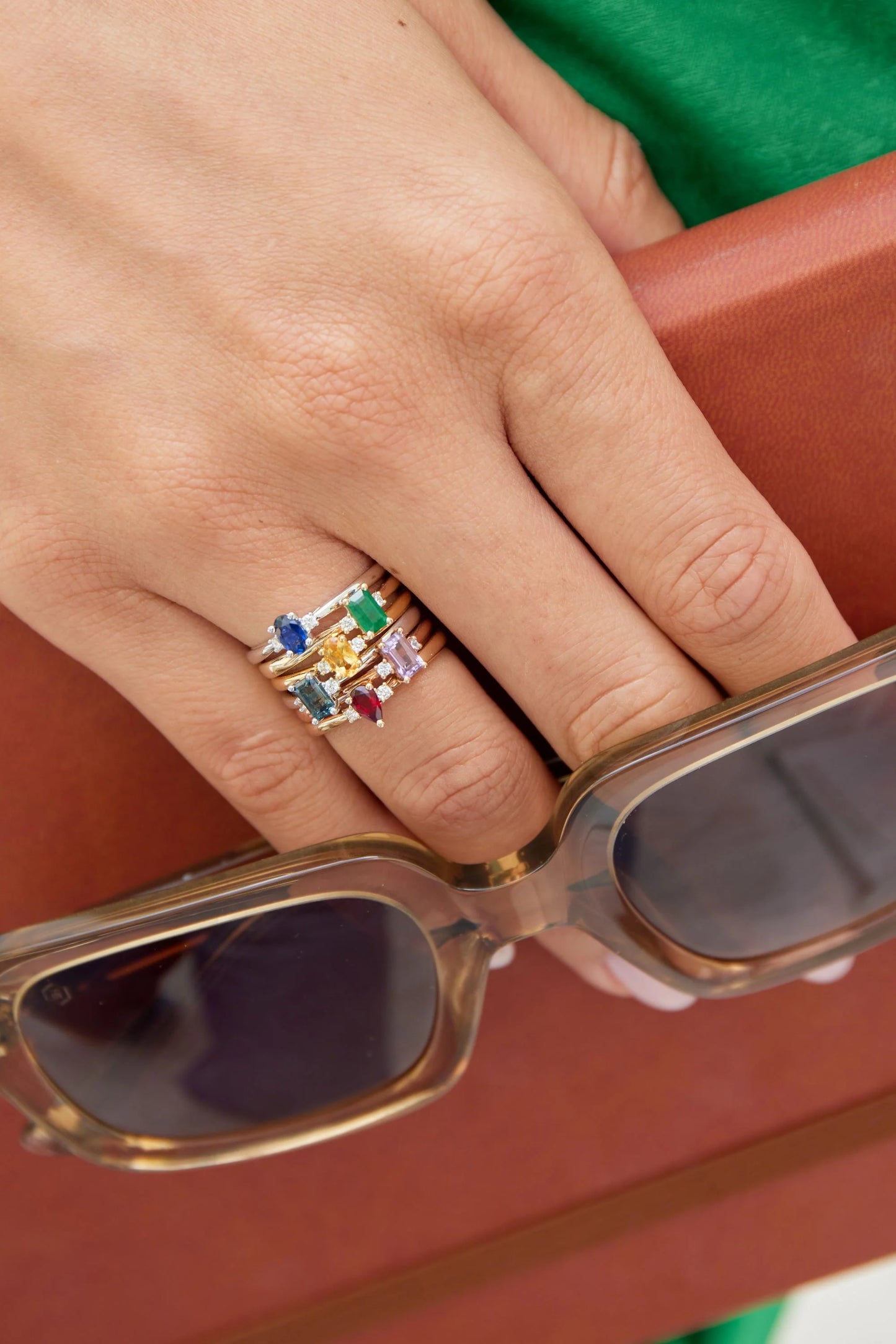 Isolde white gold ring with pear-cut blue sapphire and two round brilliant-cut diamond side stones with other stackable rings.