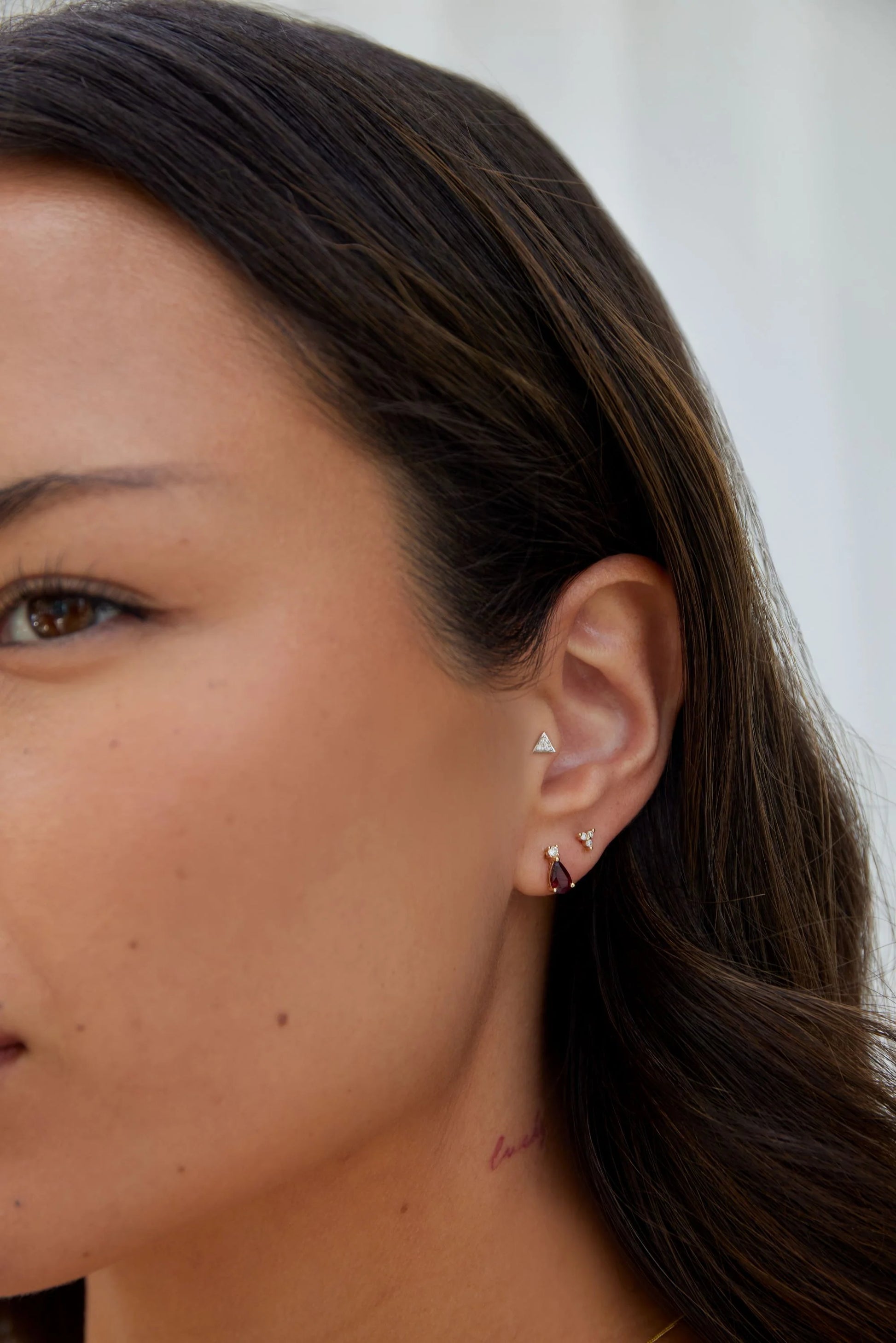 Model wearing yellow gold pear cut peridot and diamond stud earrings from the Pear Birthstone Collection