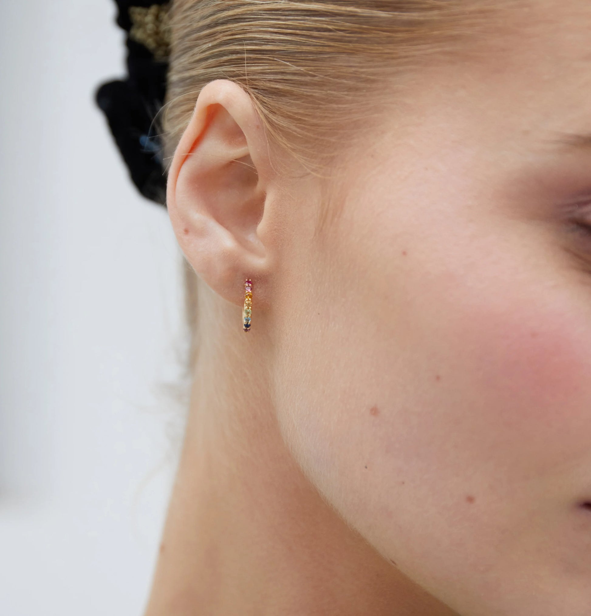 Céleste yellow gold hoop earrings claw-set with a row of round multi gemstone and post and clip fastenings.