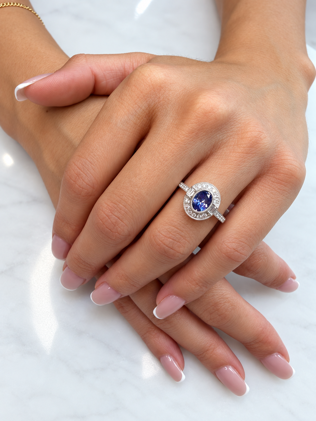 Model wearing an oval tanzanite and diamond milgrain ring in white gold, showing its size and Art Deco-inspired setting on the hand