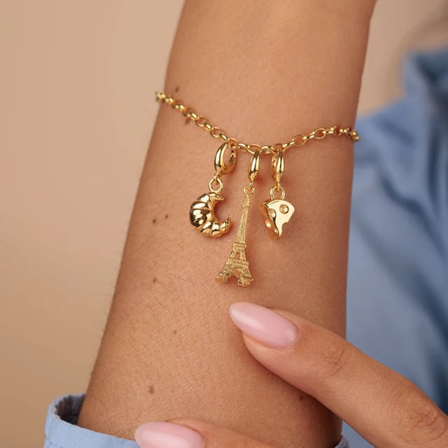 Lily Charmed gold croissant charm in 18ct gold-plated recycled sterling silver on a bracelet with Eiffel Tower charm and cheese charm